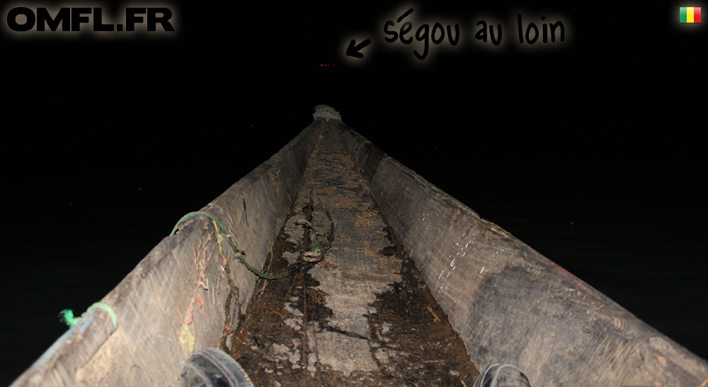 Photo de nuit sur une pirogue avec Ségou au loin